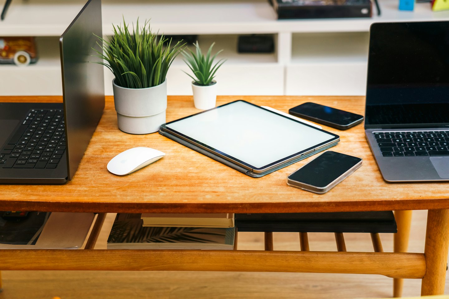 Modern laptops, tablets, and smartphones arranged on a wooden table.